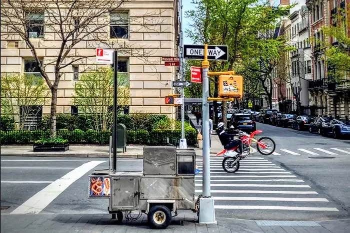 A photo of motorcyclist popping a wheelie on Fifth Avenue